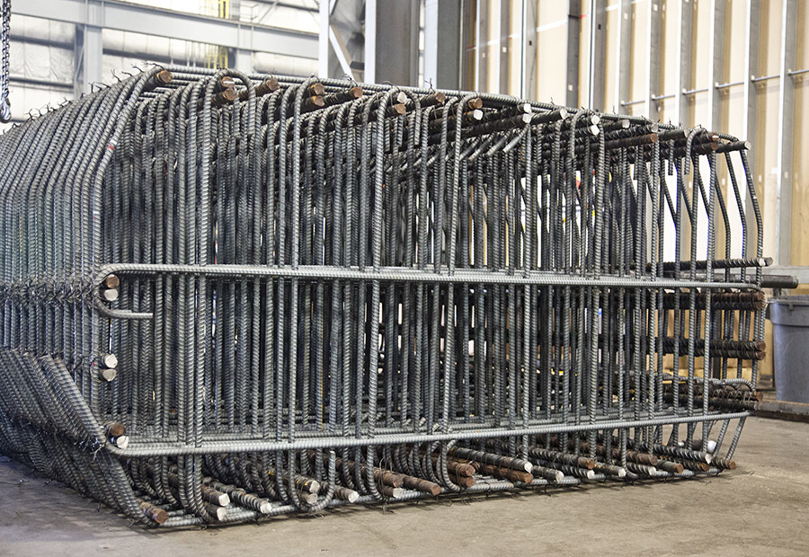 A large rebar cage sits in a warehouse.