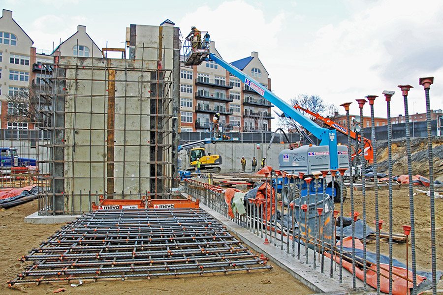 Workers survey a job site consisting of many rebar reinforced concrete areas.