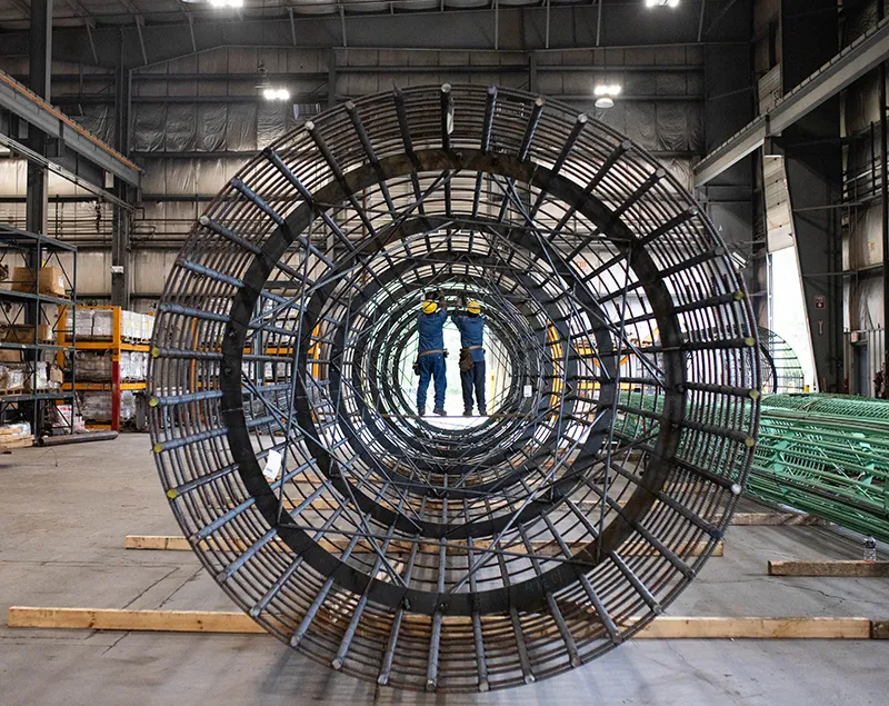 Workers fabricating Cage-Rite system while standing inside of a round rebar cage.